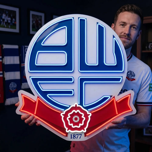 A man holding a circular Bolton Wanderers FC football club crest LED neon sign featuring the BWFC initials and the Red Rose of Lancashire ribbon glowing in blue and red light