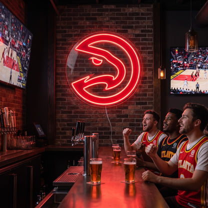 Atlanta Hawks LED neon sign on a brick wall above three fans cheering at a sports bar with basketball on TV