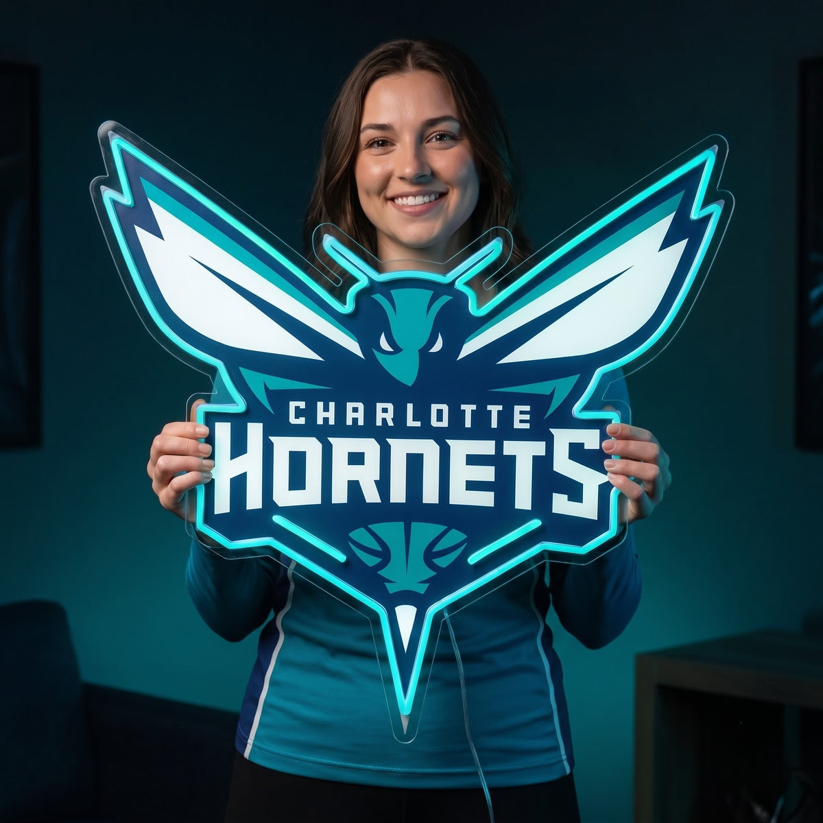 Woman holding a teal Charlotte Hornets LED neon sign shaped like the team's hornet logo