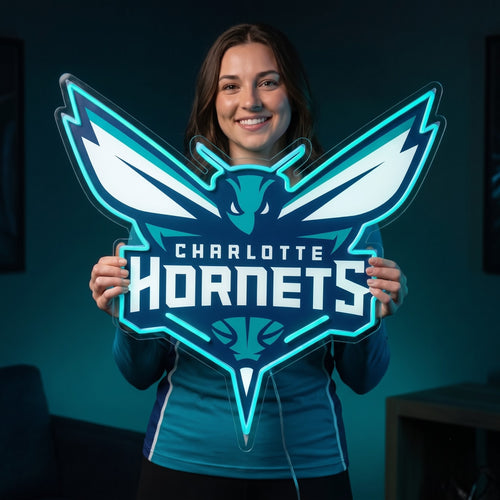 Woman holding a teal Charlotte Hornets LED neon sign shaped like the team's hornet logo