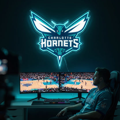 Charlotte Hornets LED neon sign glowing teal above dual monitors showing basketball in a gaming room
