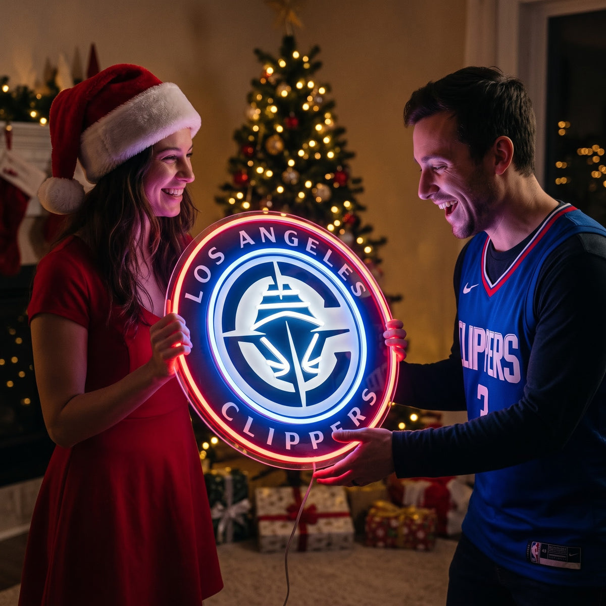 Couple exchanging a Los Angeles Clippers LED neon sign as a Christmas gift by the tree