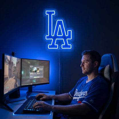 Los Angeles Dodgers LED neon sign - A fan in a Dodgers jersey sits at a computer desk beneath a glowing blue Los Angeles Dodgers LA logo neon sign.