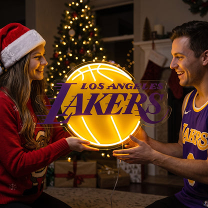 Couple exchanging a Los Angeles Lakers LED neon sign as a Christmas gift by the tree