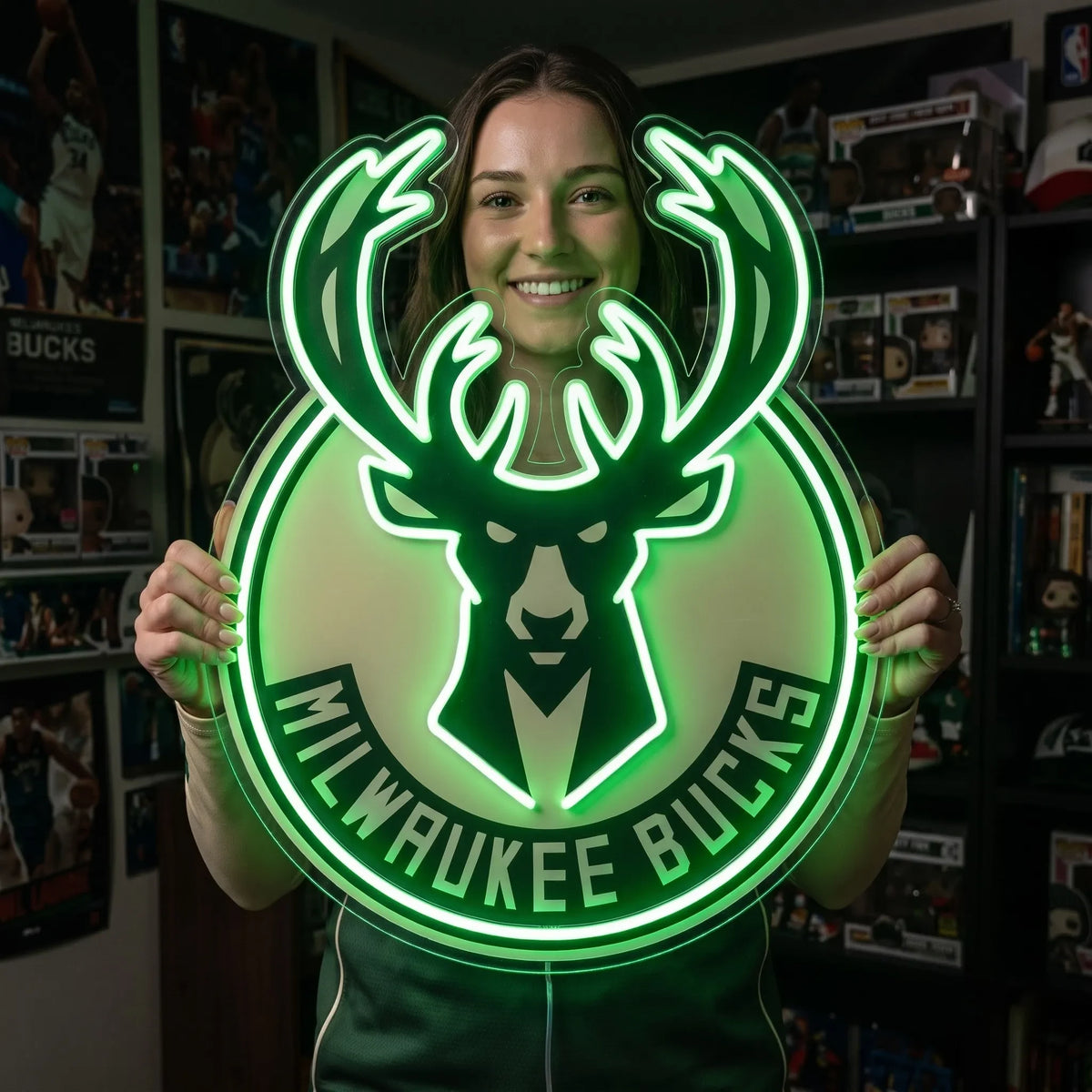 Milwaukee Bucks LED neon sign - A smiling woman holds a large green Milwaukee Bucks deer logo neon sign in a fan room.