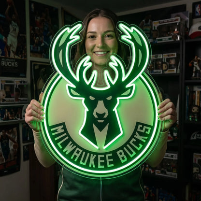 Milwaukee Bucks LED neon sign - A smiling woman holds a large green Milwaukee Bucks deer logo neon sign in a fan room.