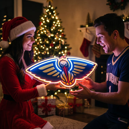 Couple exchanging a New Orleans Pelicans LED neon sign as a Christmas gift by the tree
