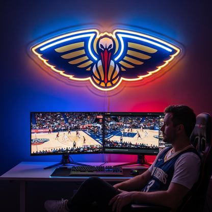 New Orleans Pelicans LED neon sign above a gaming setup with a fan watching basketball