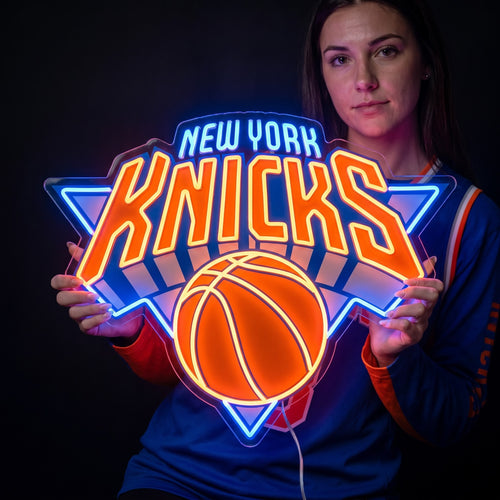 Woman holding a New York Knicks LED neon sign with orange lettering, a basketball and bright blue outlines
