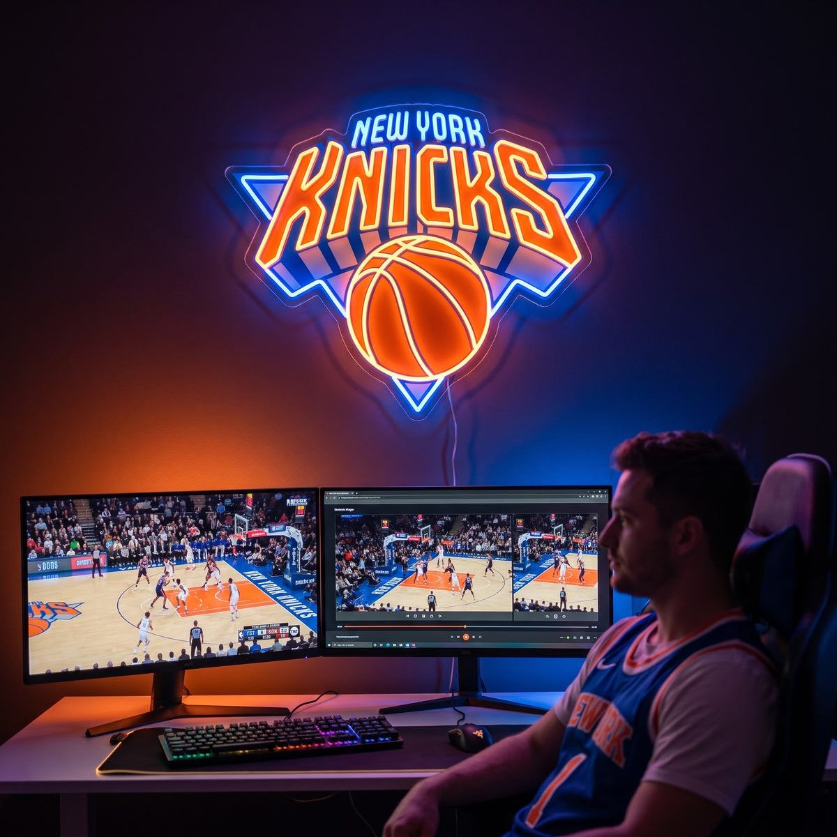 Orange and blue New York Knicks LED neon sign above dual monitors showing basketball in a fan's game room