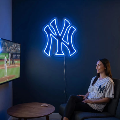 New York Yankees LED neon sign - A woman in a pinstripe Yankees jersey relaxes in a chair beside a glowing blue New York Yankees NY logo neon sign.