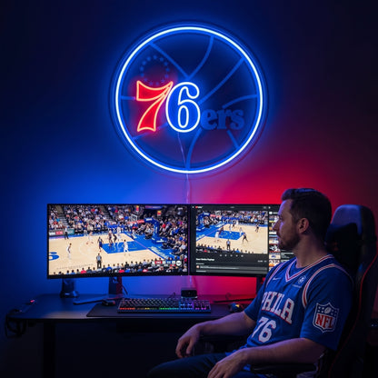 Philadelphia 76ers LED neon sign above dual monitors showing basketball in a game room with blue and red lighting