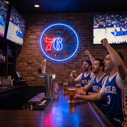 Philadelphia 76ers LED neon sign on a brick wall above three fans cheering at a sports bar with basketball on TV