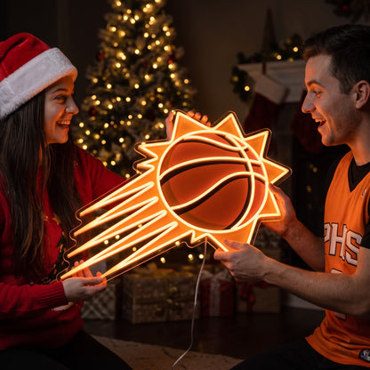Couple exchanging a Phoenix Suns LED neon sign as a Christmas gift by the tree