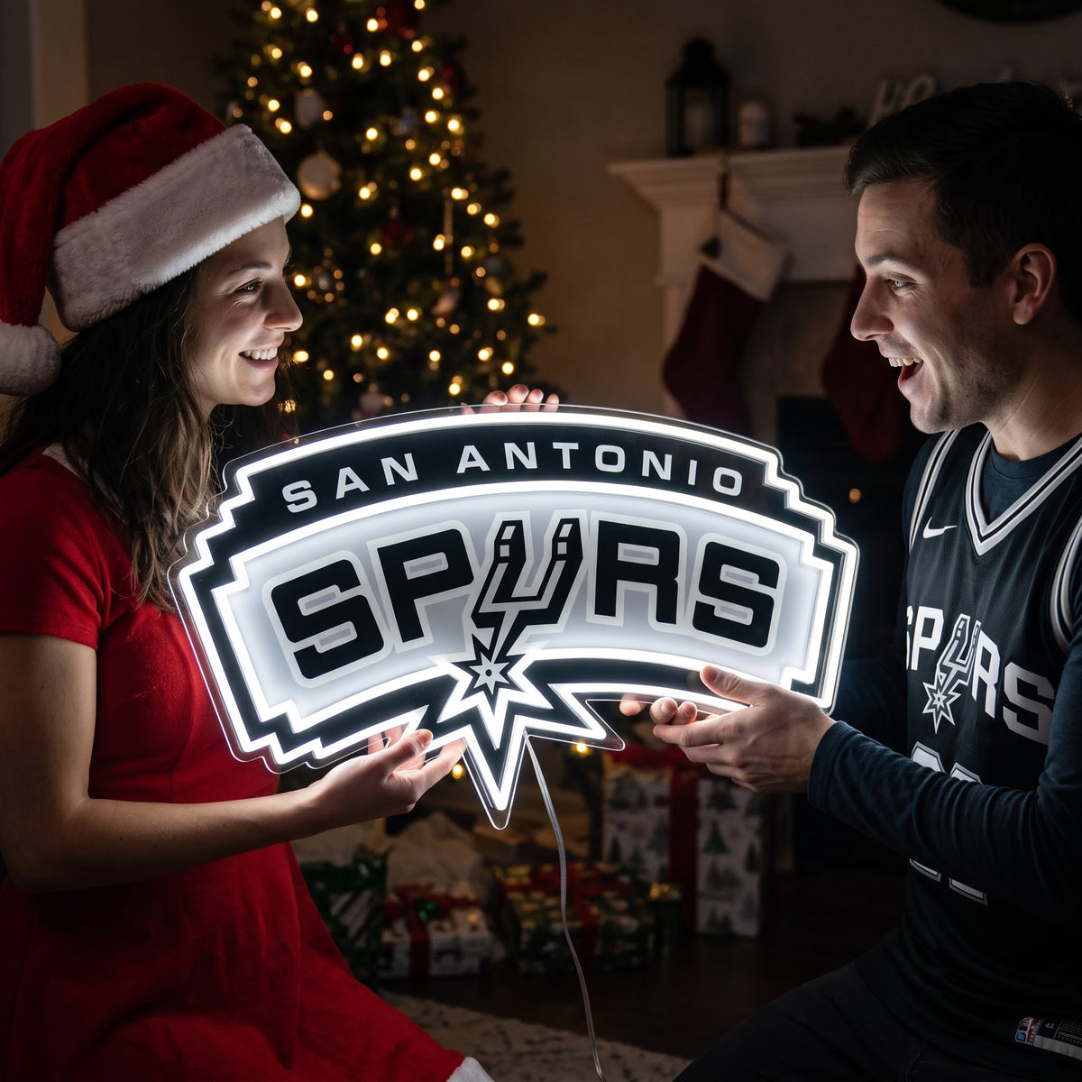 Couple exchanging a San Antonio Spurs LED neon sign as a Christmas gift by the tree