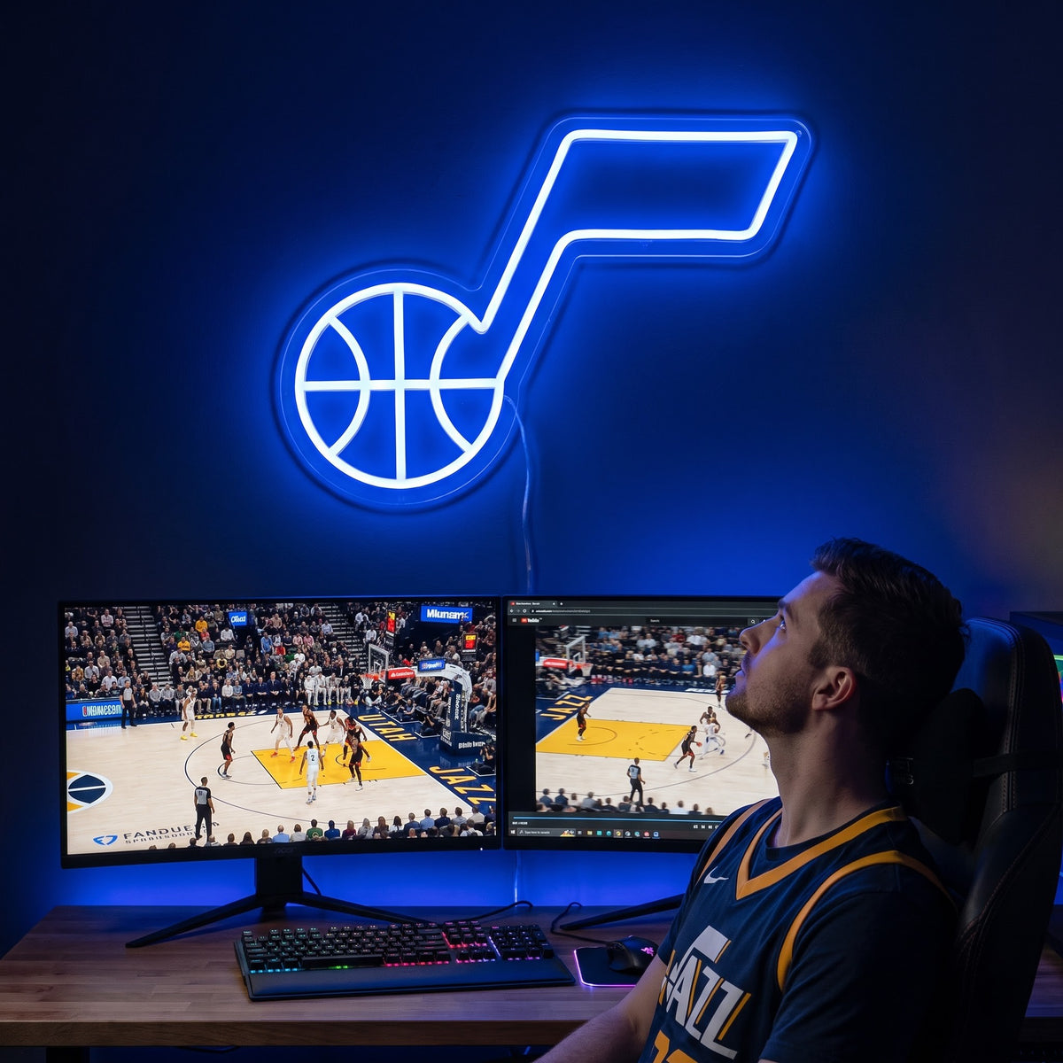Utah Jazz LED neon sign above a gaming setup with a fan watching basketball